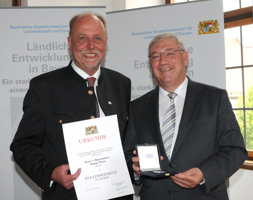 Freudestrahlend nimmt Michael Pelzer die Urkunde und die Silbermedaille entgegen.